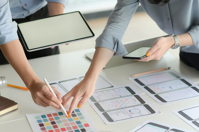 Cropped shot of young UX designer team working on smartphone application project with using digital tablet in modern office room.